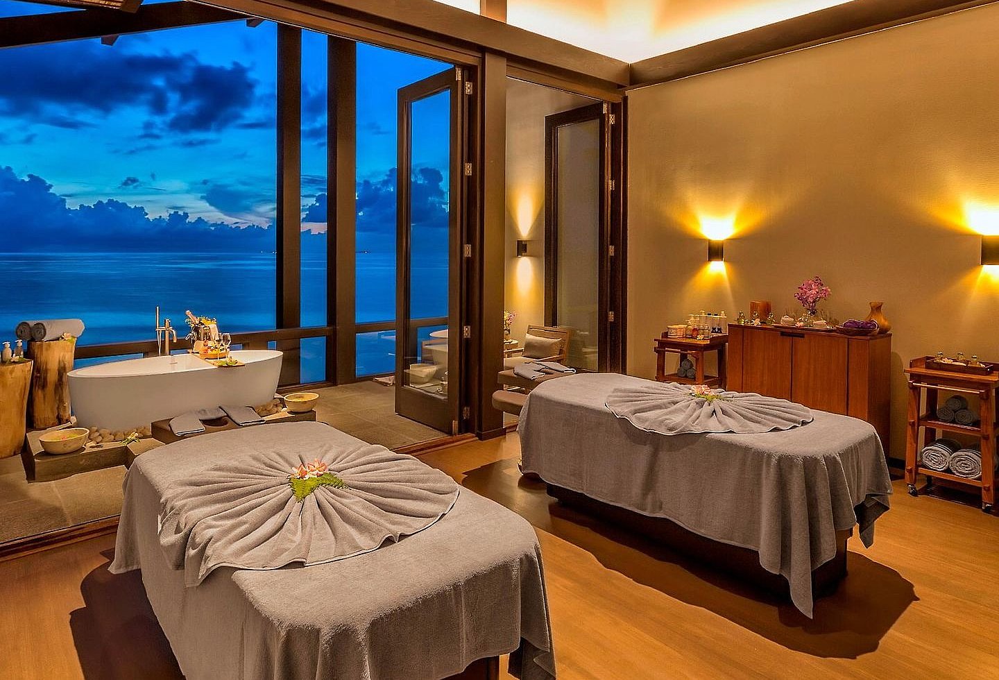 Spa Behandlungsraum bei Nacht, Innen 2 Liegen in Grau, auf der Terrasse freistehende Badewanne