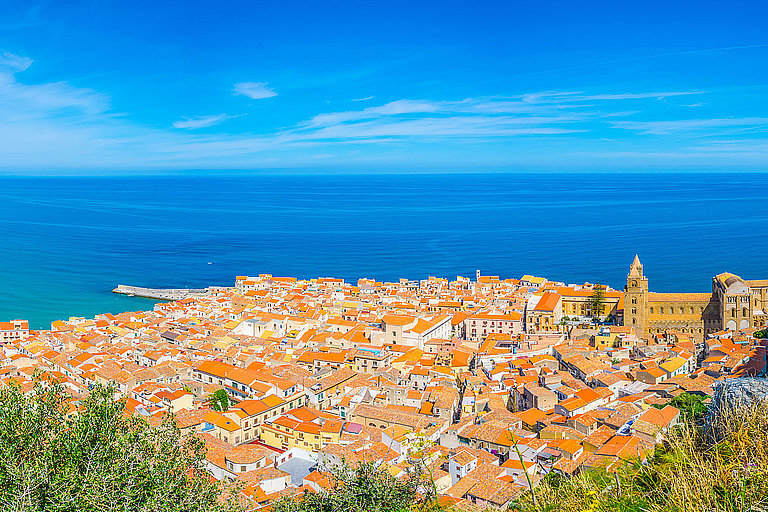 Blumenwiese über Taormina mit Blick auf Küste, Häuser und blaues Meer.