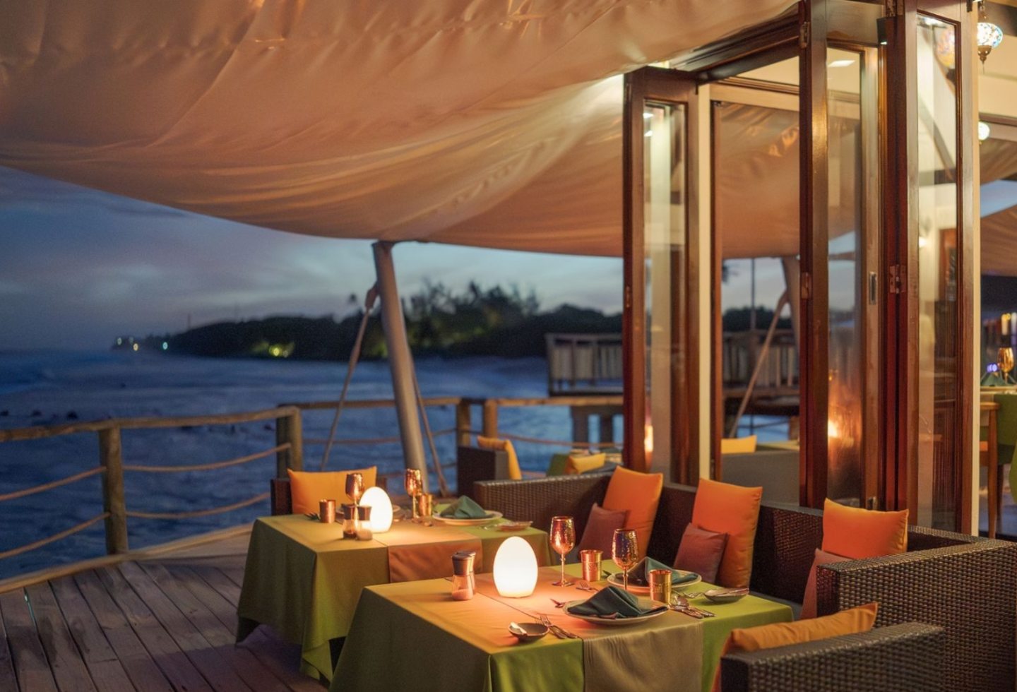 Romantisch gedeckter Tisch mit Kerzen auf einer Terrasse mit Blick aufs Meer.