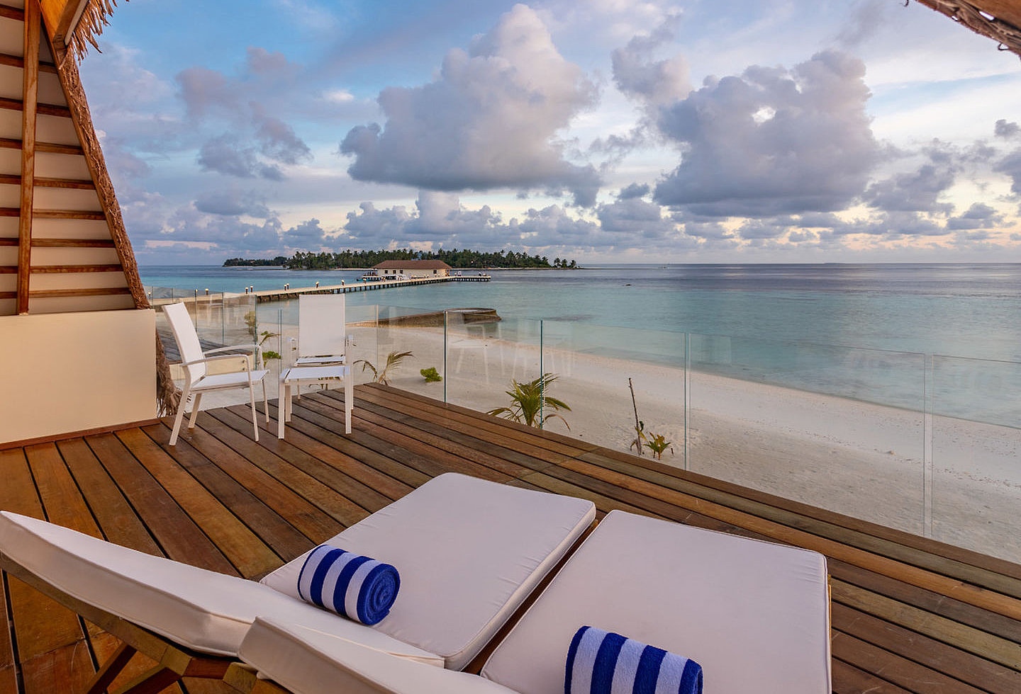 Ausblick auf das weite Meer und Strand von einem Balkon mit Sonnenliegen.