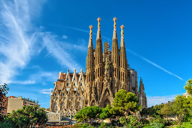 Sagrada Familia erhebt sich mit ihren Türmen vor blauem Himmel in Barcelona.