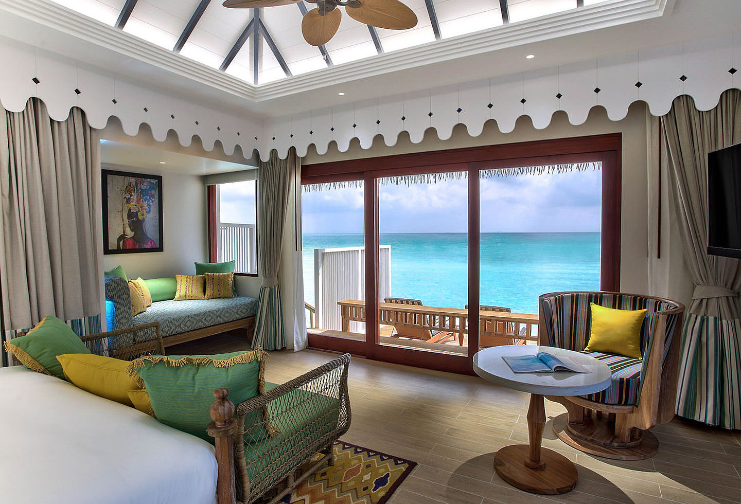 Schlafzimmer des Wasserbungalows mit Holzmöbeln und Blick auf die Lagune