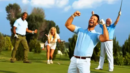 Vier Golfer jubeln auf dem Grün, einer kniet vor Freude mit geballten Fäusten. 