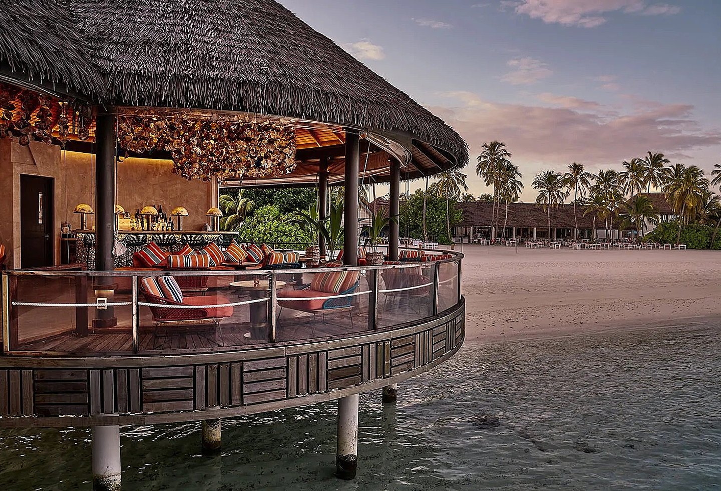 Blick auf ein Restaurant am Strand mit Blick auf tropische Pflanzen und das Meer.